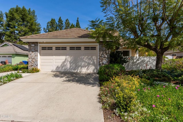 view of front of house with a tile roof, concrete driveway, a garage, and stone siding