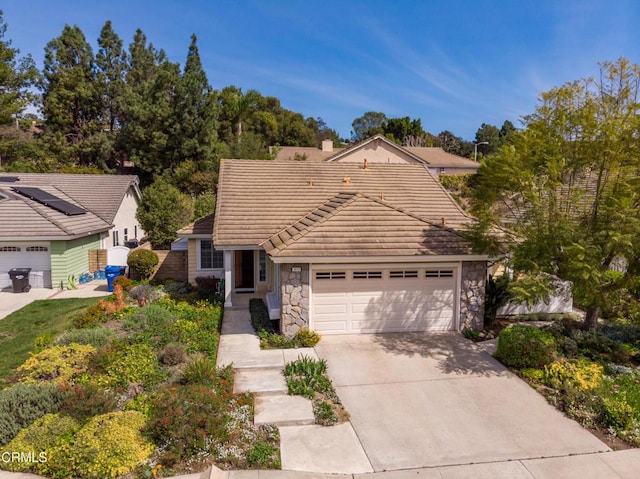 view of front of property with a tiled roof, a chimney, a garage, stone siding, and driveway