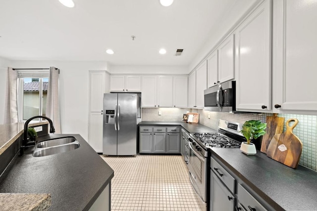 kitchen with a sink, stainless steel appliances, dark countertops, and visible vents