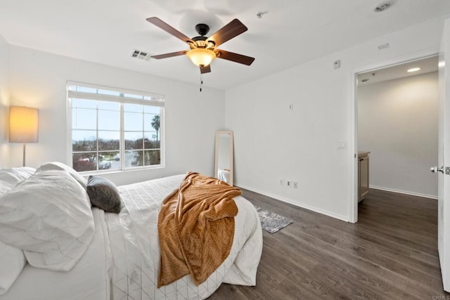 bedroom with dark wood-style floors, visible vents, a ceiling fan, and baseboards