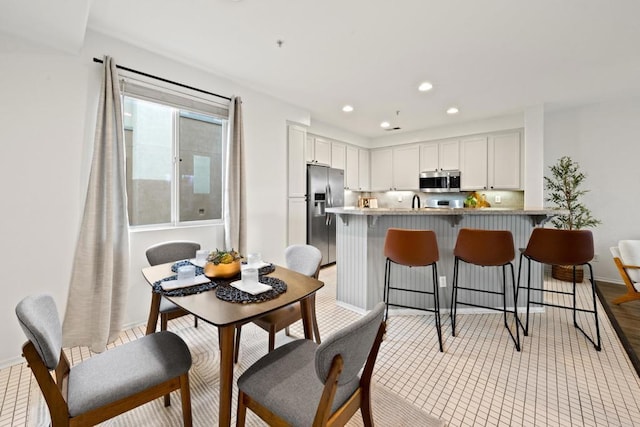 kitchen with stainless steel appliances, a kitchen breakfast bar, a peninsula, and white cabinetry