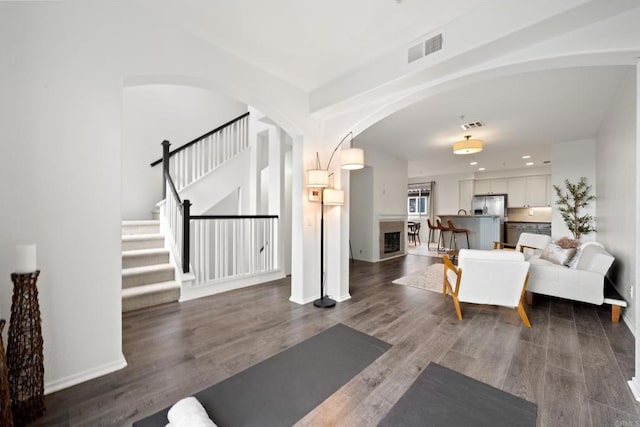 interior space featuring visible vents, arched walkways, wood finished floors, and stairway