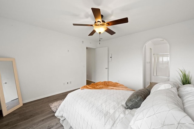 bedroom featuring arched walkways, a ceiling fan, baseboards, and wood finished floors