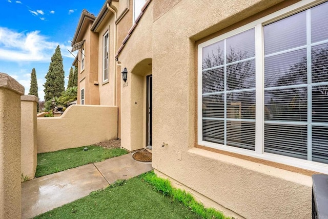 view of exterior entry with a balcony and stucco siding