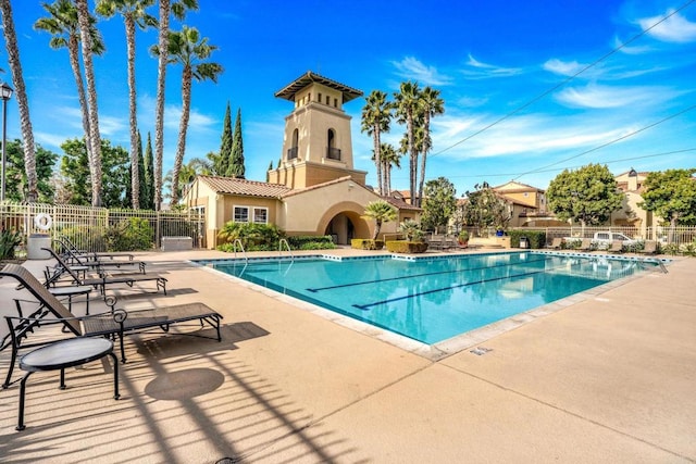 community pool with a patio area and fence