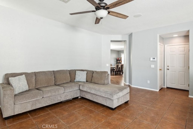 unfurnished living room featuring baseboards, ceiling fan, and dark tile patterned flooring