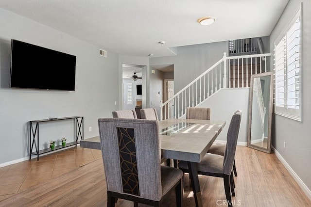 dining space featuring visible vents, stairway, baseboards, and wood finished floors