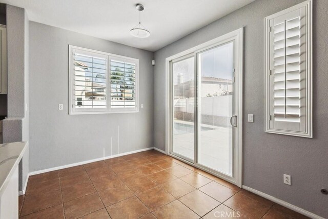 unfurnished dining area with tile patterned floors and baseboards