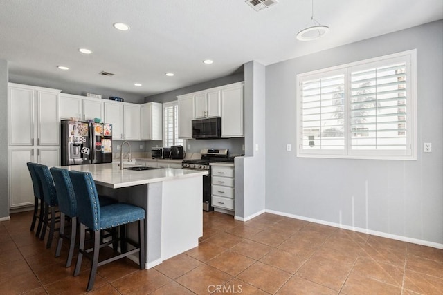 kitchen with fridge with ice dispenser, a breakfast bar, gas stove, white cabinets, and light countertops