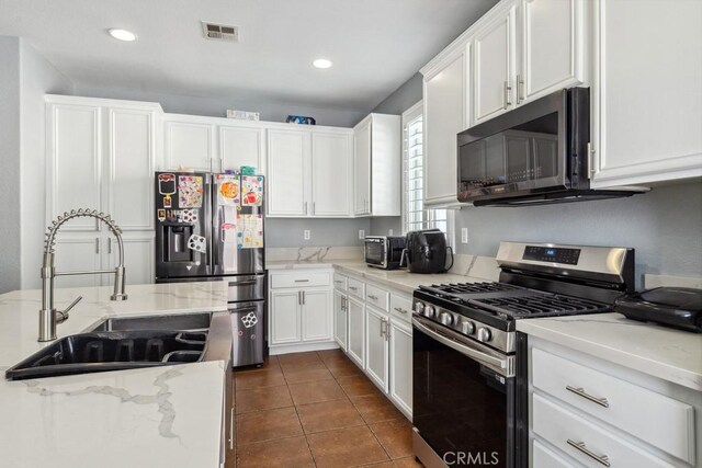 kitchen with visible vents, dark tile patterned flooring, a sink, white cabinets, and appliances with stainless steel finishes