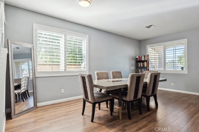 dining room with visible vents, plenty of natural light, baseboards, and wood finished floors