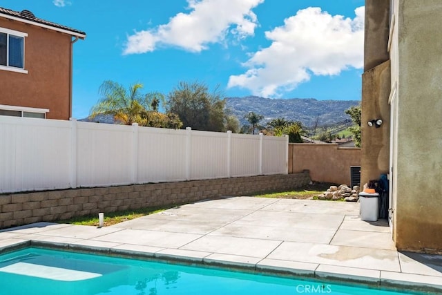 view of pool featuring a fenced in pool, a mountain view, a fenced backyard, and a patio