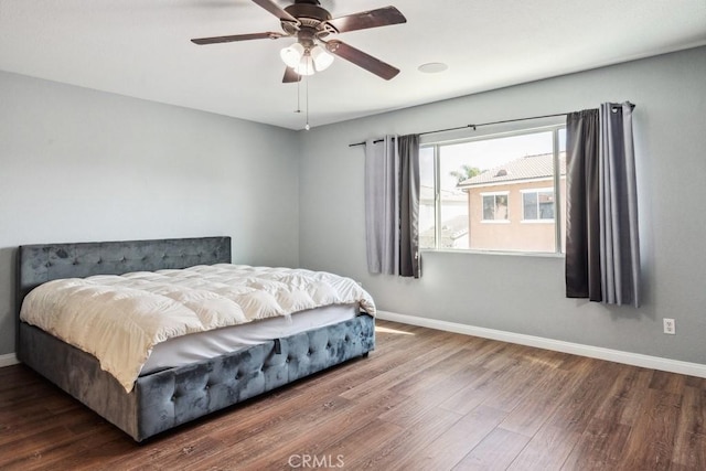 bedroom featuring baseboards, wood finished floors, and a ceiling fan