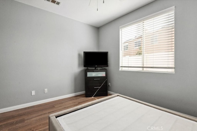 bedroom featuring visible vents, baseboards, wood finished floors, and a ceiling fan