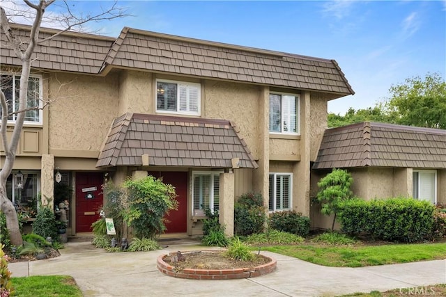 view of front of property with mansard roof and stucco siding