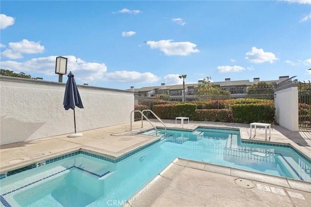 community pool featuring a patio area, a jacuzzi, and fence