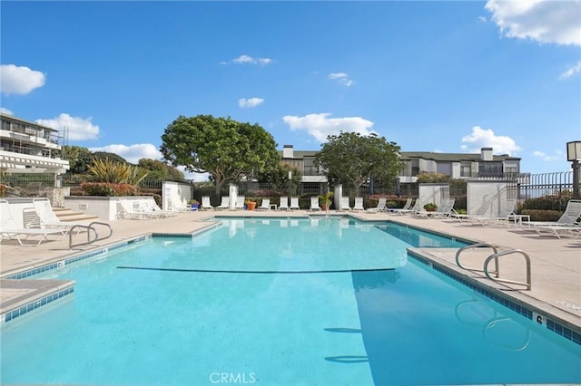 pool with a patio area and fence