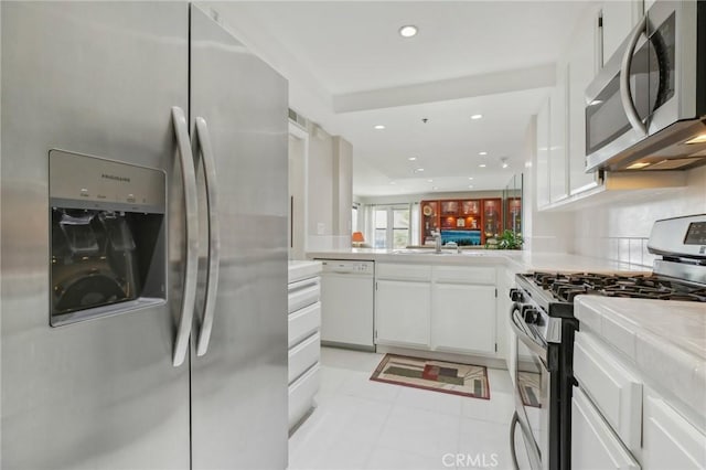 kitchen featuring a sink, recessed lighting, stainless steel appliances, white cabinets, and light countertops