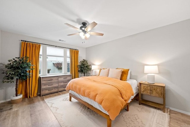 bedroom with light wood finished floors, visible vents, a ceiling fan, and baseboards