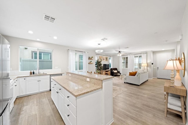 kitchen featuring light wood-style flooring, visible vents, white cabinets, and a kitchen island