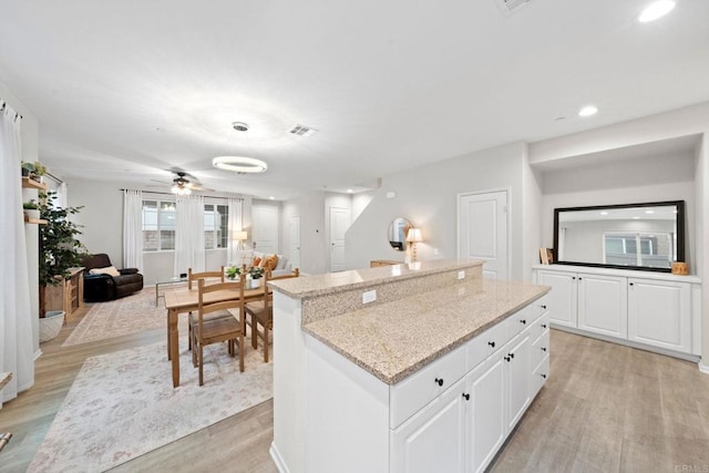 kitchen featuring a kitchen island, light wood-type flooring, and light stone countertops