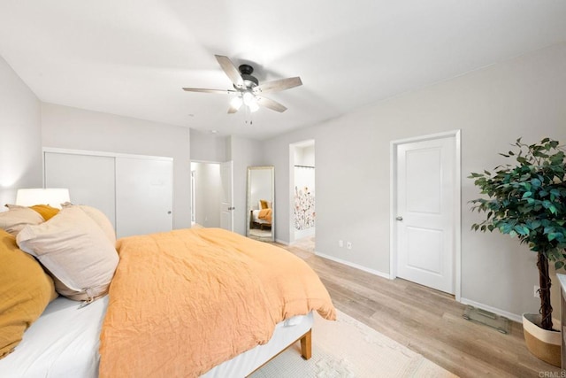 bedroom featuring a ceiling fan, baseboards, a closet, light wood-type flooring, and connected bathroom