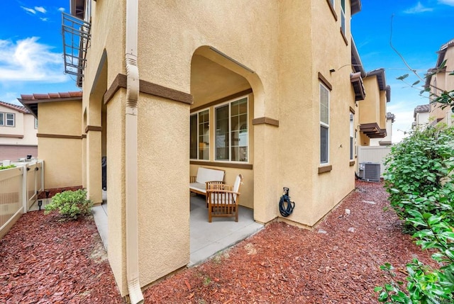 exterior space with central AC unit, a patio area, fence, and stucco siding