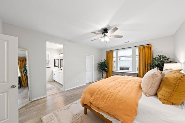 bedroom featuring connected bathroom, baseboards, light wood-style floors, and a ceiling fan