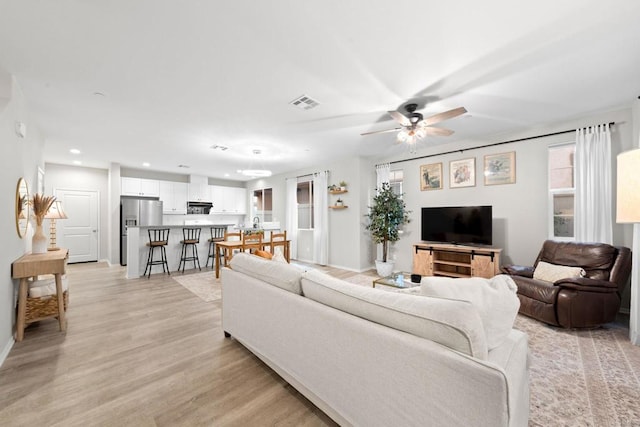 living room with a ceiling fan, baseboards, visible vents, recessed lighting, and light wood-type flooring