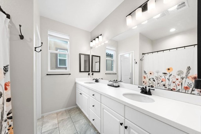 bathroom with double vanity, visible vents, baseboards, and a sink