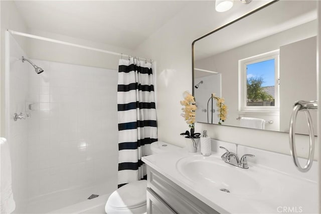 bathroom with toilet, tiled shower, and vanity