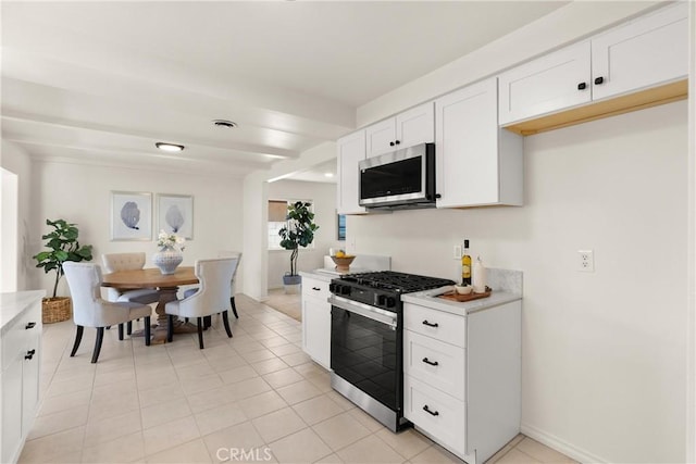 kitchen with visible vents, light countertops, gas range, white cabinetry, and stainless steel microwave