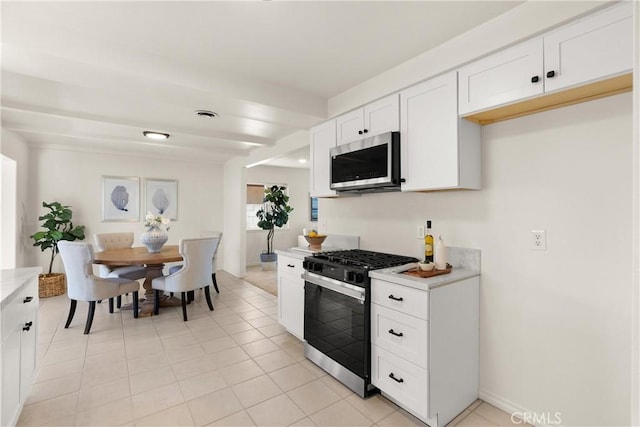 kitchen with visible vents, white cabinets, stainless steel microwave, light countertops, and range with gas stovetop