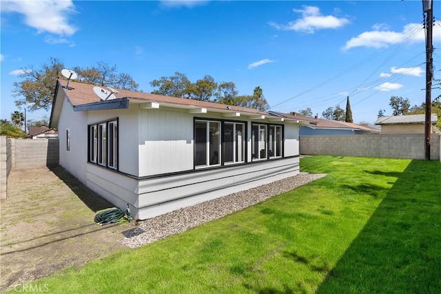 rear view of property featuring a yard and a fenced backyard