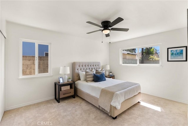 bedroom with light colored carpet, a ceiling fan, and baseboards