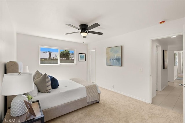 bedroom with a ceiling fan, light tile patterned floors, light colored carpet, and baseboards