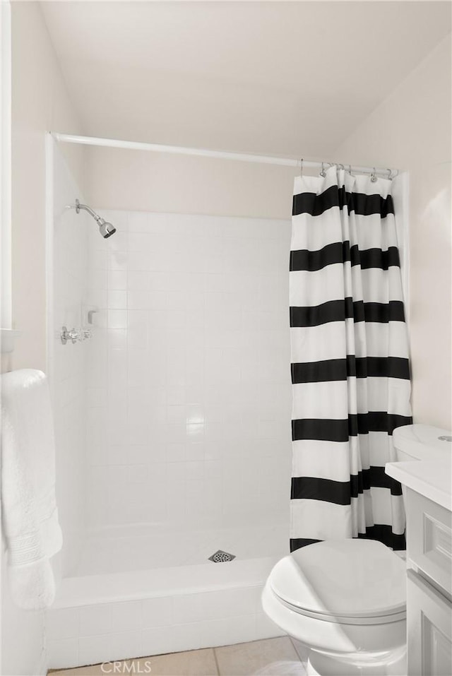 bathroom featuring tile patterned floors, vanity, a tile shower, and toilet