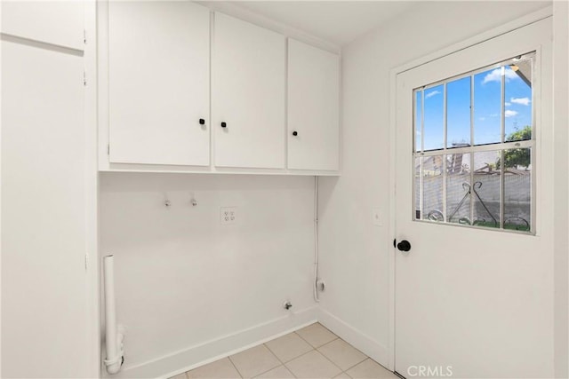 clothes washing area with light tile patterned floors, baseboards, and cabinet space