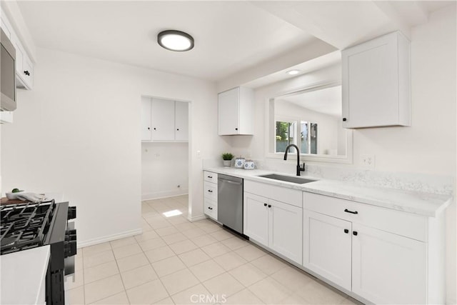 kitchen featuring baseboards, light tile patterned floors, white cabinets, stainless steel appliances, and a sink