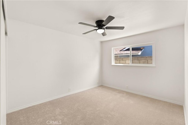 carpeted spare room with baseboards and a ceiling fan