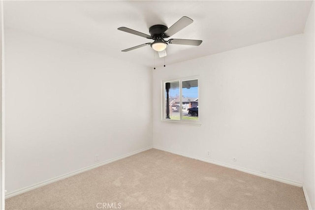 empty room with baseboards, ceiling fan, and light carpet