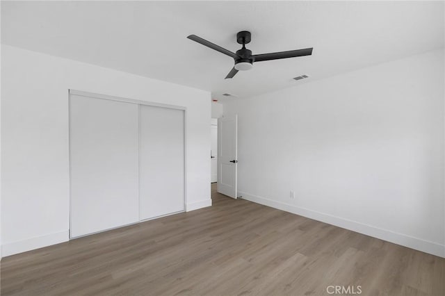 unfurnished bedroom featuring a ceiling fan, visible vents, baseboards, a closet, and light wood-type flooring