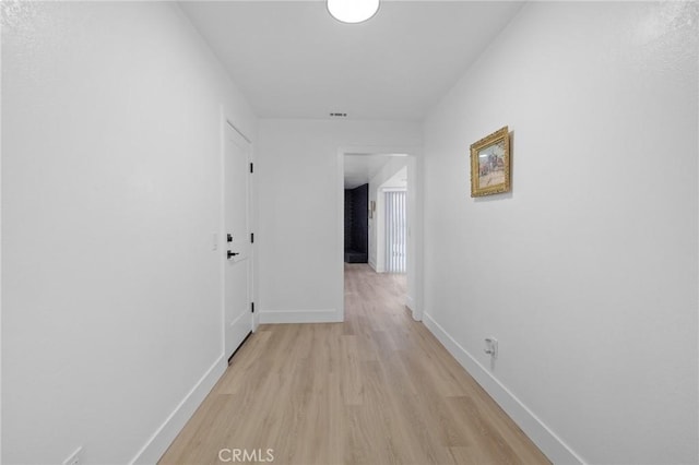 hallway with light wood-type flooring, baseboards, and visible vents