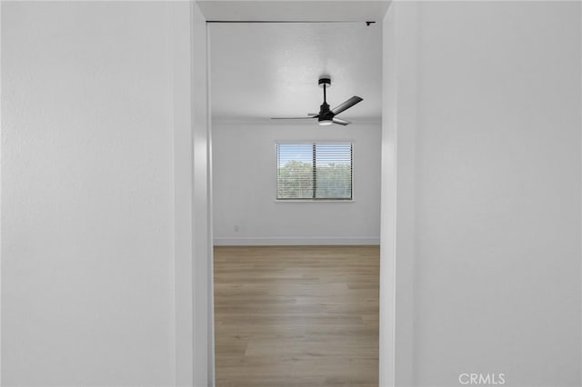 empty room featuring a ceiling fan, wood finished floors, and baseboards