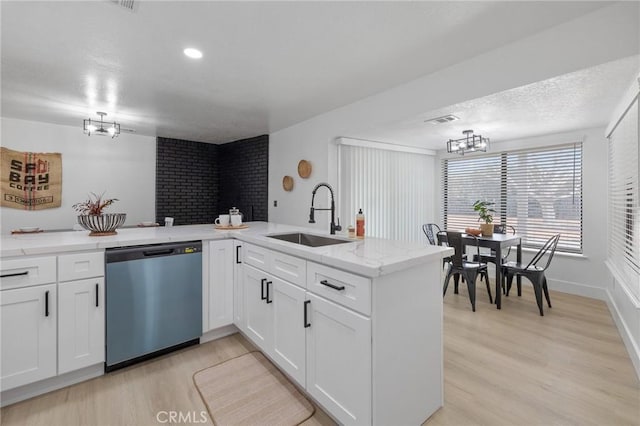 kitchen featuring visible vents, dishwasher, light wood-style flooring, white cabinetry, and a sink