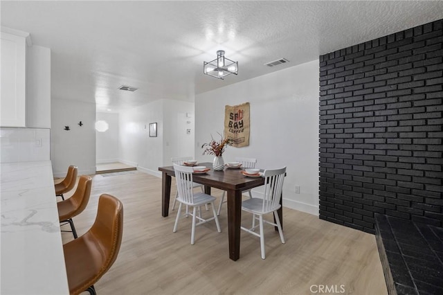 dining room featuring visible vents, a textured ceiling, light wood-type flooring, and baseboards