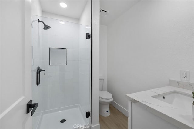 bathroom featuring toilet, wood finished floors, visible vents, and a stall shower