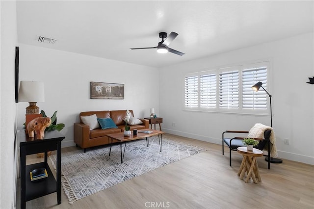 living room featuring a ceiling fan, wood finished floors, visible vents, and baseboards