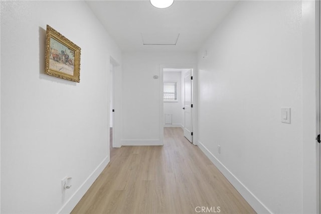 corridor featuring attic access, light wood-type flooring, and baseboards