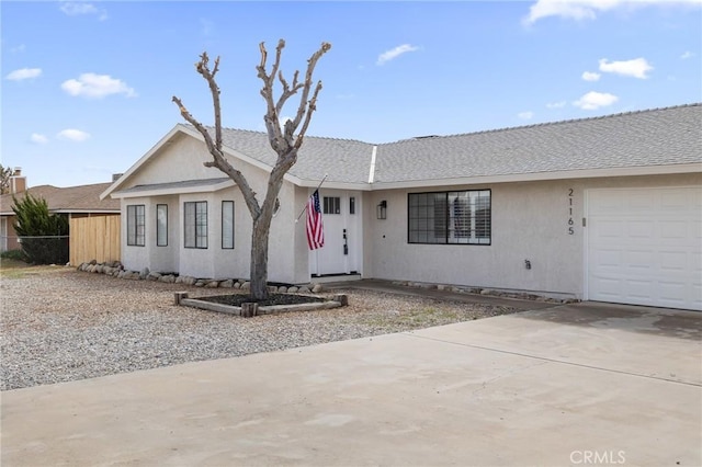 ranch-style home featuring concrete driveway, stucco siding, a garage, and a shingled roof